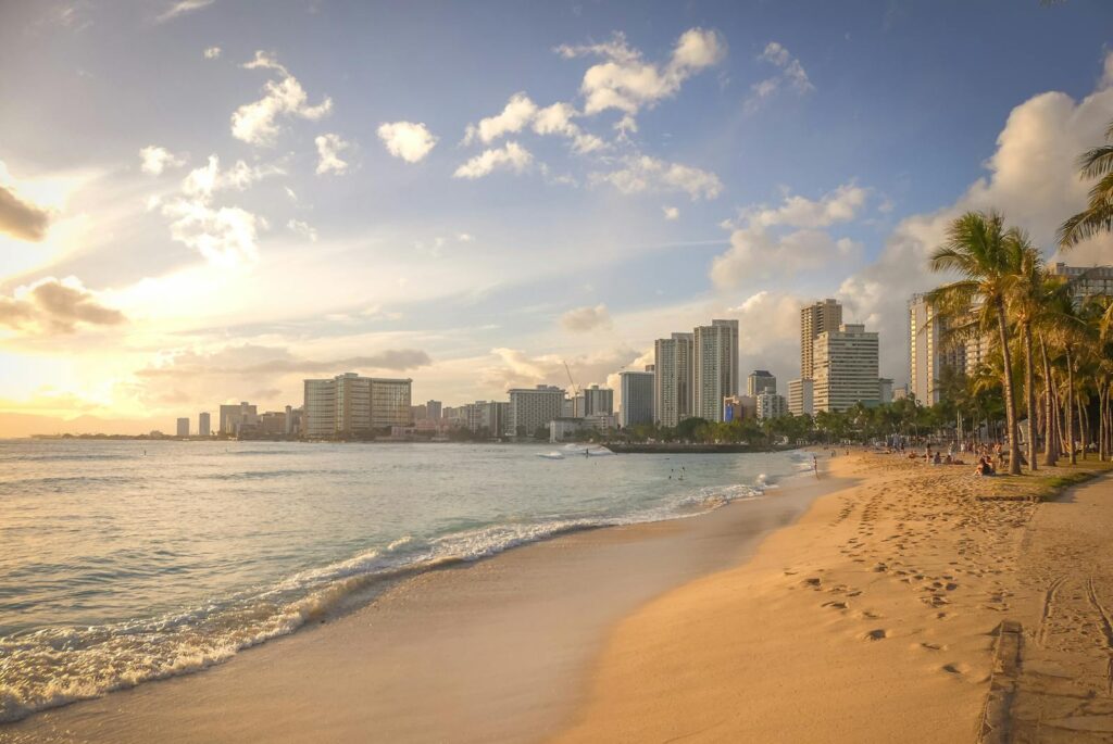 Experience the serene beauty of Honolulu's beach at sunset, featuring the city's stunning skyline.