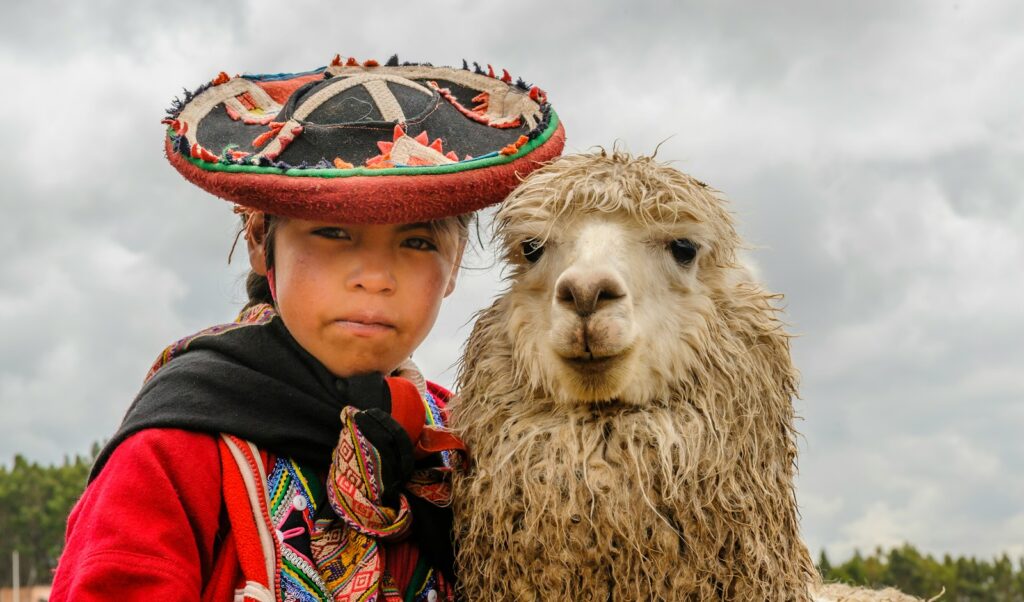 a woman in a sombrero standing next to a llama